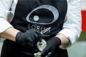 Persona abriendo una ostra en un evento gastronómico