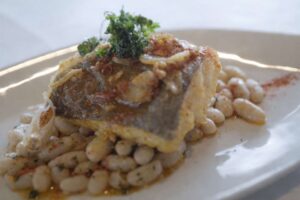 Plato de bacalao a la llauna servido con judías blancas