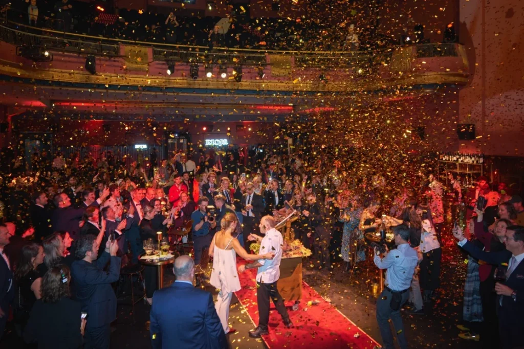 Celebración del centenario de Rioja con confeti y asistentes aplaudiendo.