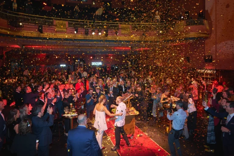 Celebración del centenario de Rioja con confeti y asistentes aplaudiendo.