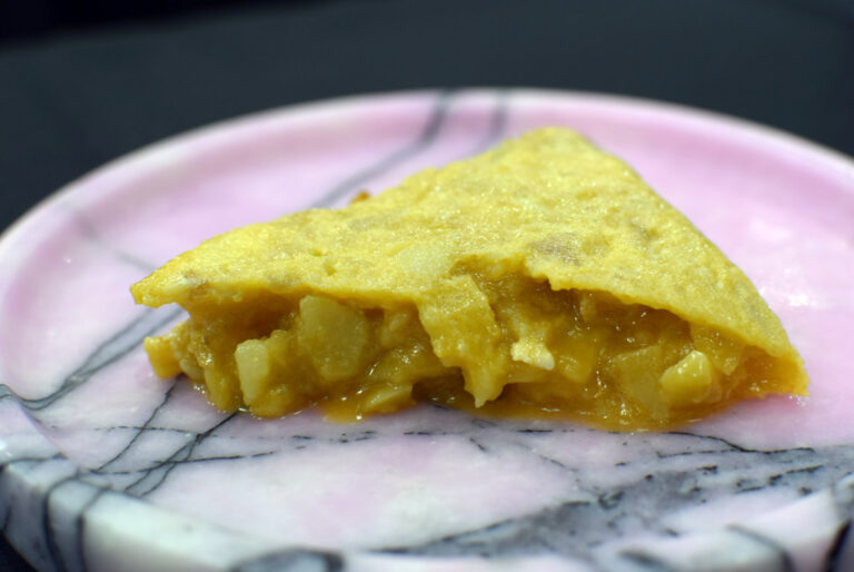 Porción de tortilla de patata presentada en un plato rosa