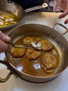 Plato de patatas a la importancia con cocochas en una sartén
