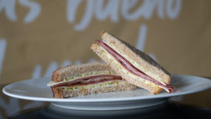 Sándwich de pastrami con salsa de cítricos y queso en un plato.