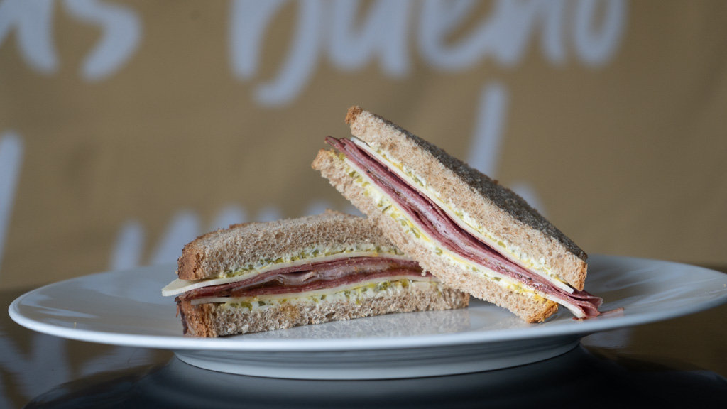 Sándwich de pastrami con salsa de cítricos y queso en un plato.