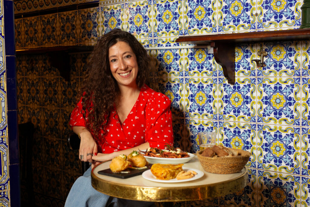 Mujer sonriente con platos de comida española en un bar