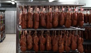 Piezas de sobrasada colgadas en un estante en una fábrica