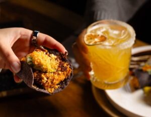 Taco de maíz azul con relleno y bebida en restaurante Bakan