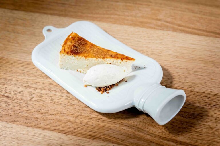 Porción de tarta de queso con helado sobre un plato blanco