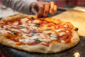 Pizza gourmet con mozzarella y albahaca en un evento de cocina