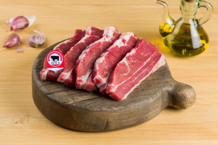Trozos de carne de Ávila en una tabla de madera con ajo y aceite de oliva