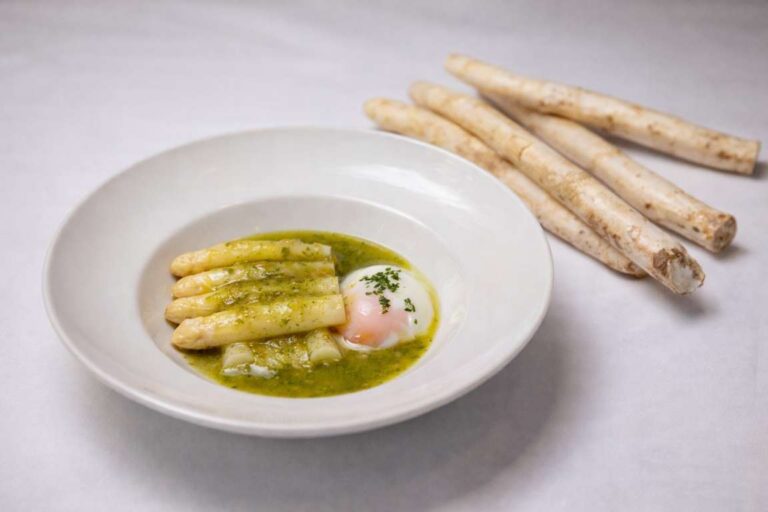 Plato de espárrago guisado con huevo escalfado en salsa verde