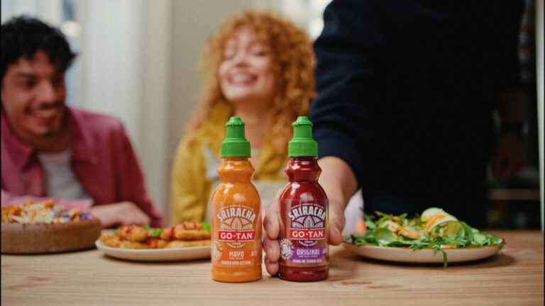 Botellas de salsa Sriracha Go-Tan en una mesa con comida