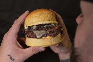 Hamburguesa gourmet con carne y queso en mano
