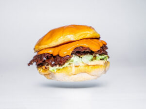 Hamburguesa con carne, lechuga y salsa sobre fondo blanco