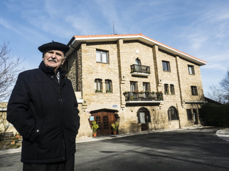 Hombre mayor frente a un edificio de piedra en San Sebastián