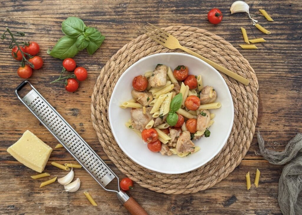 Plato de pasta con carne de conejo, tomates cherry y albahaca fresca
