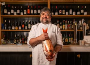 Chef Alex Santamaría sosteniendo un besugo en su restaurante Infame.