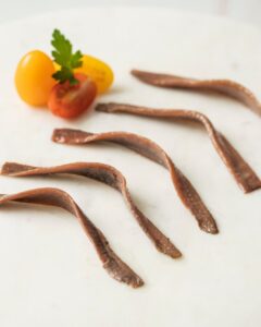 Filetes de anchoa del Cantábrico sobre una tabla con tomates cherry