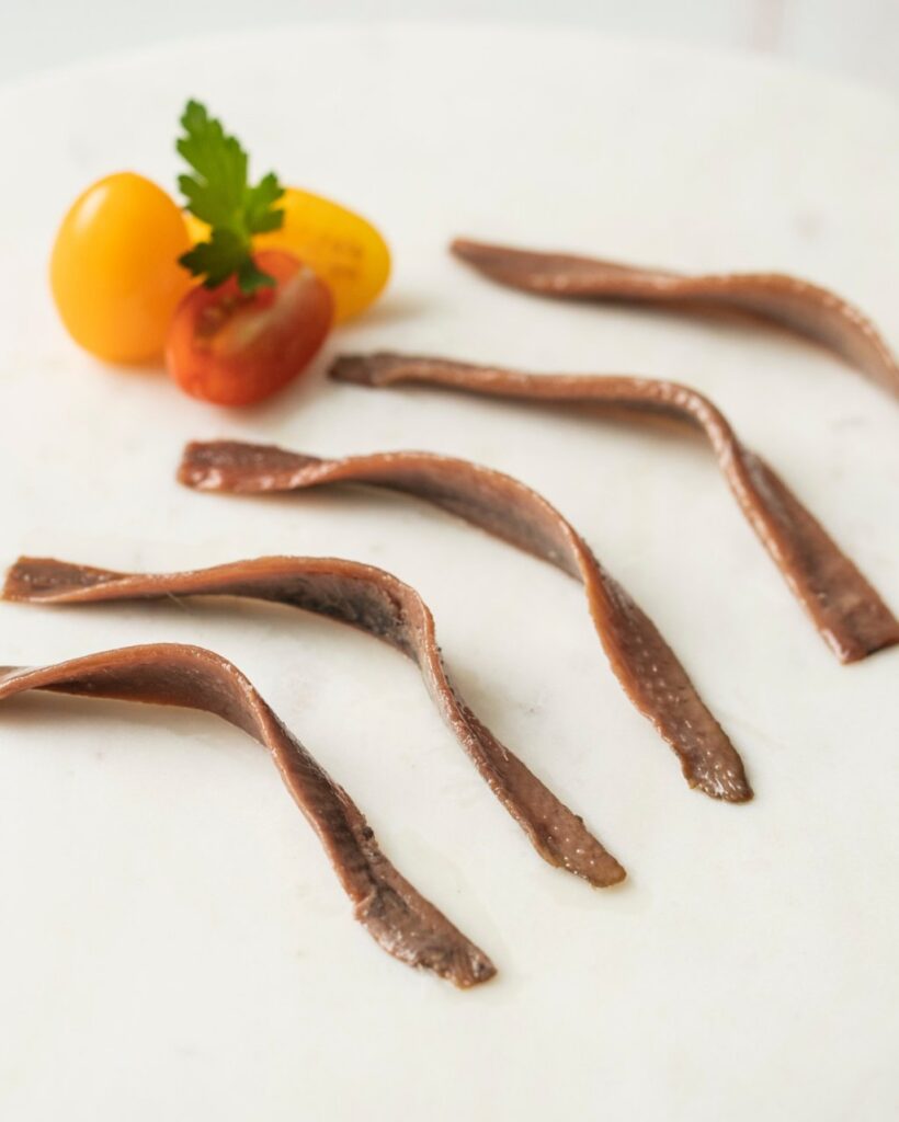 Filetes de anchoa del Cantábrico sobre una tabla con tomates cherry