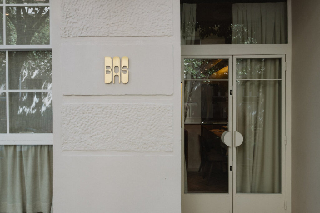 Entrada del restaurante BAS en Madrid con su distintivo logo dorado.