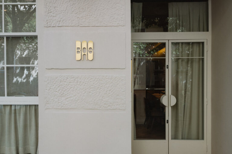 Entrada del restaurante BAS en Madrid con su distintivo logo dorado.