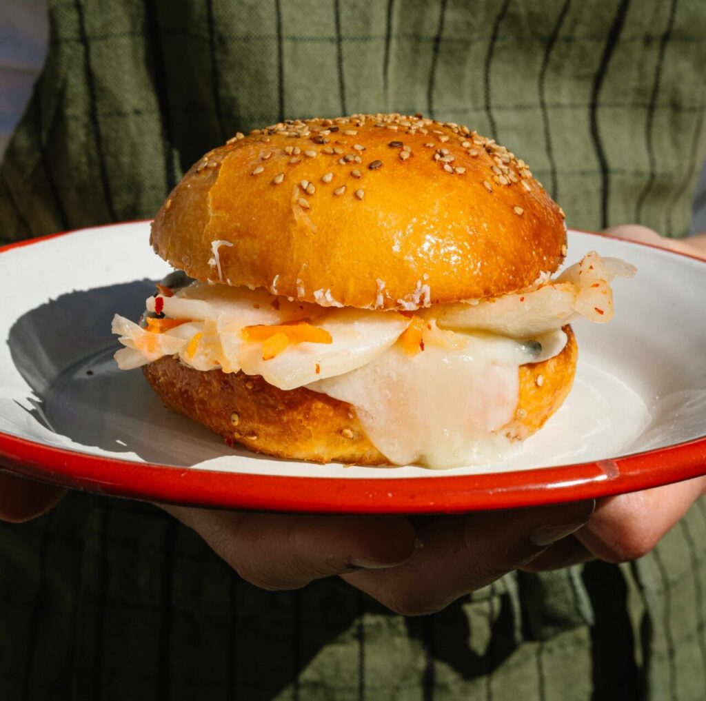 Bocadillo de brioche con kimchi y queso fundido en un plato