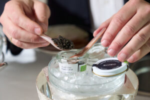 Mano sirviendo caviar ecológico de Riofrío en un plato