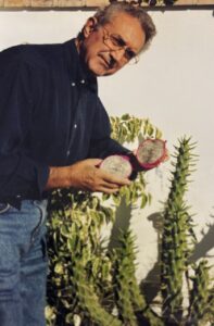 Julián Díaz Robledo sosteniendo fruta exótica frente a cactus
