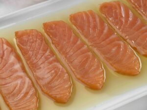 Lomos de salmón ahumado en aceite de oliva en un plato blanco