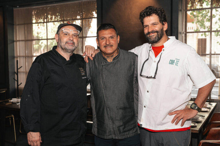 Tres chefs posando juntos en un evento gastronómico