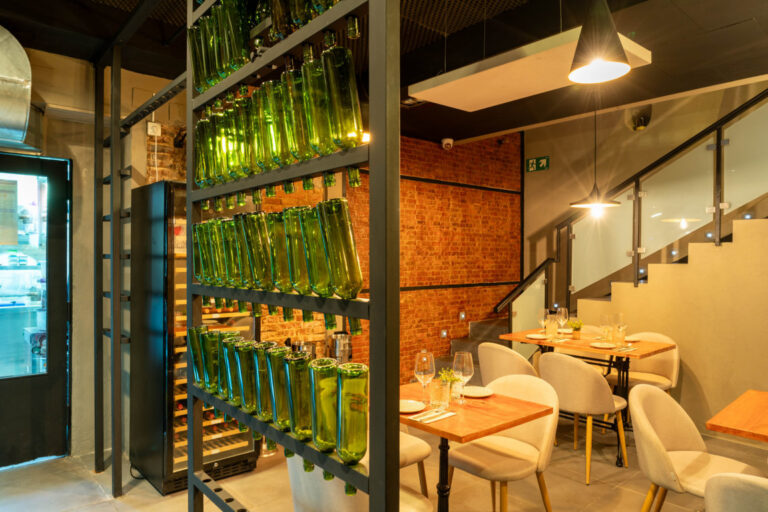 Interior del restaurante Picona con botellas verdes y mesas elegantes.