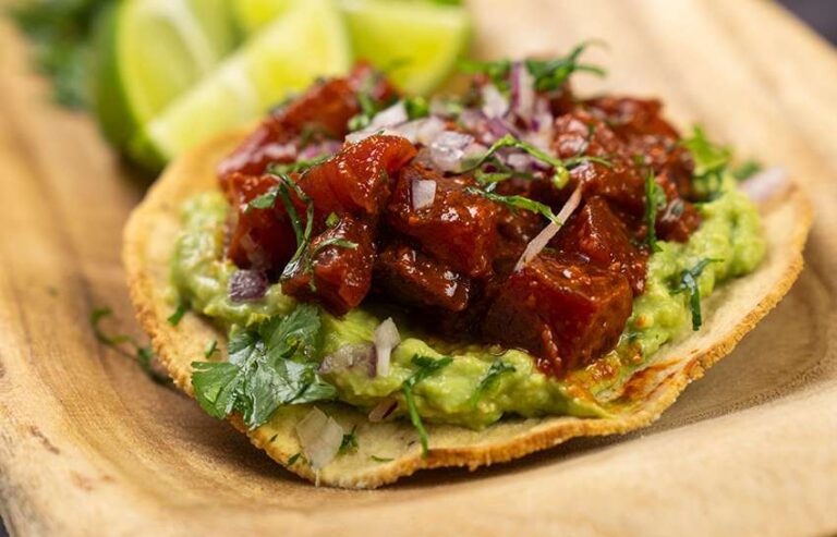 Taco con guacamole y carne en un plato de madera