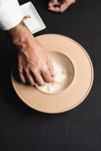 Chef añadiendo ingredientes a un plato de tallarines de calamar