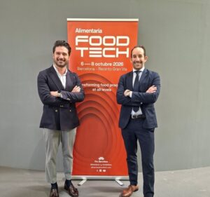 Dos profesionales posando frente al cartel de Alimentaria FoodTech en Barcelona