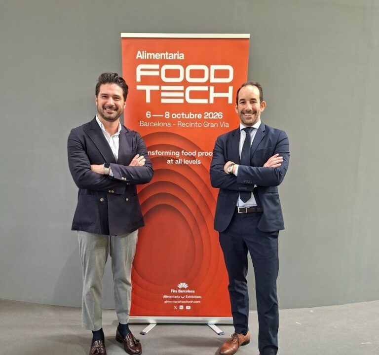 Dos profesionales posando frente al cartel de Alimentaria FoodTech en Barcelona