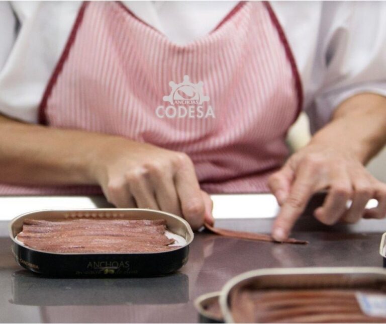 Manos fileteando anchoas de la marca Codesa en un entorno artesanal.