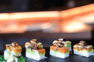 Plato de sushi con capas de aguacate y pescado en un restaurante