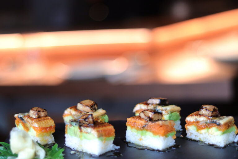 Plato de sushi con capas de aguacate y pescado en un restaurante