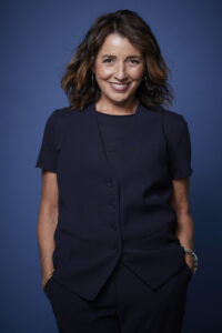 Ana Escobar, experta en comunicación gastronómica, sonriente en un fondo azul.
