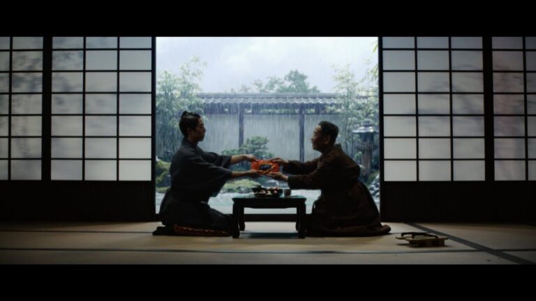 Dos personas en un ambiente japonés intercambiando barritas de surimi.