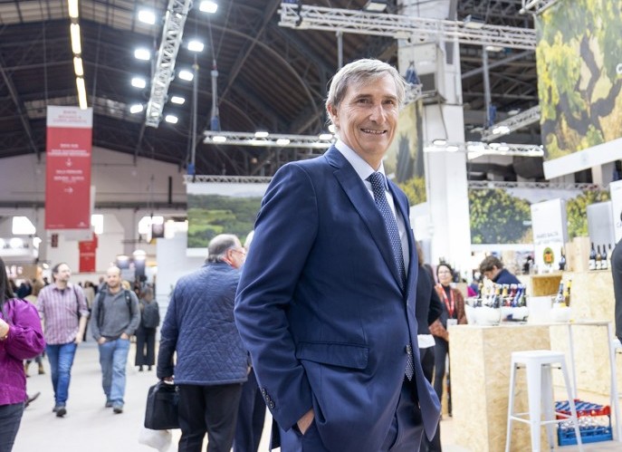 Hombre sonriente en un evento de vino con público y stands