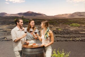 Tres personas brindando con vino en un viñedo de Lanzarote