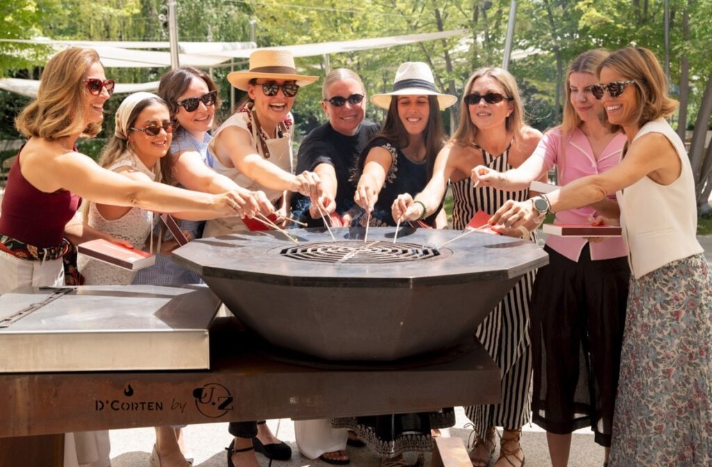Grupo de mujeres disfrutando de una marbacoa con salmón en un ambiente festivo.