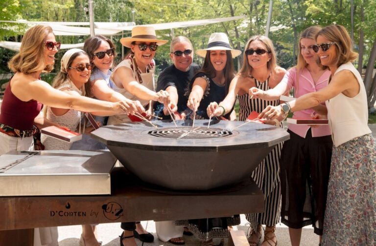 Grupo de mujeres disfrutando de una marbacoa con salmón en un ambiente festivo.