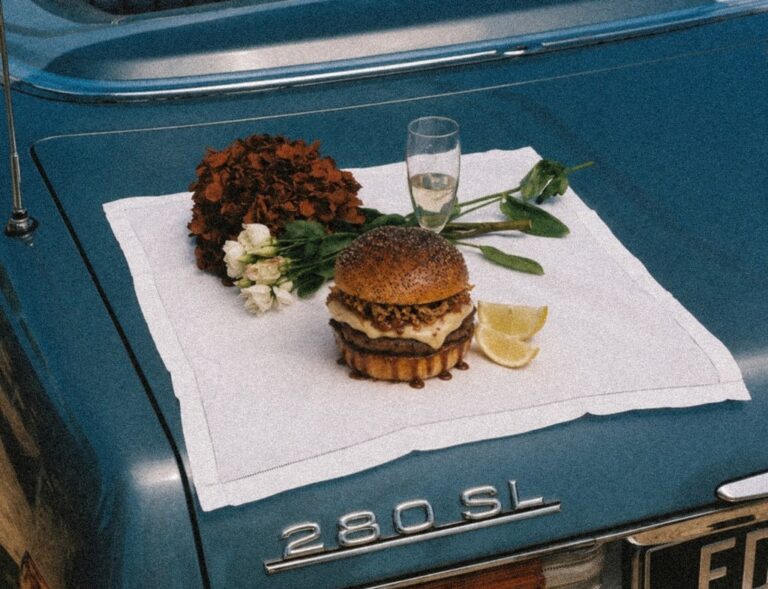 Hamburguesa Paquito sobre una mesa con flores y limón