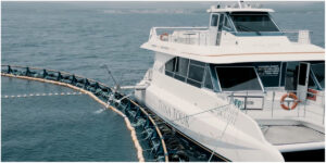 Catamarán Tuna Tour en el mar, rodeado de redes de acuicultura.