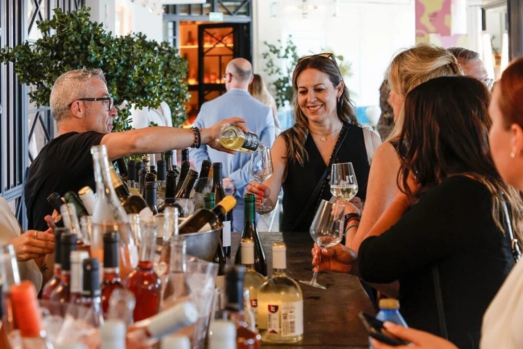 Personas disfrutando de una cata de vinos en un evento urbano.