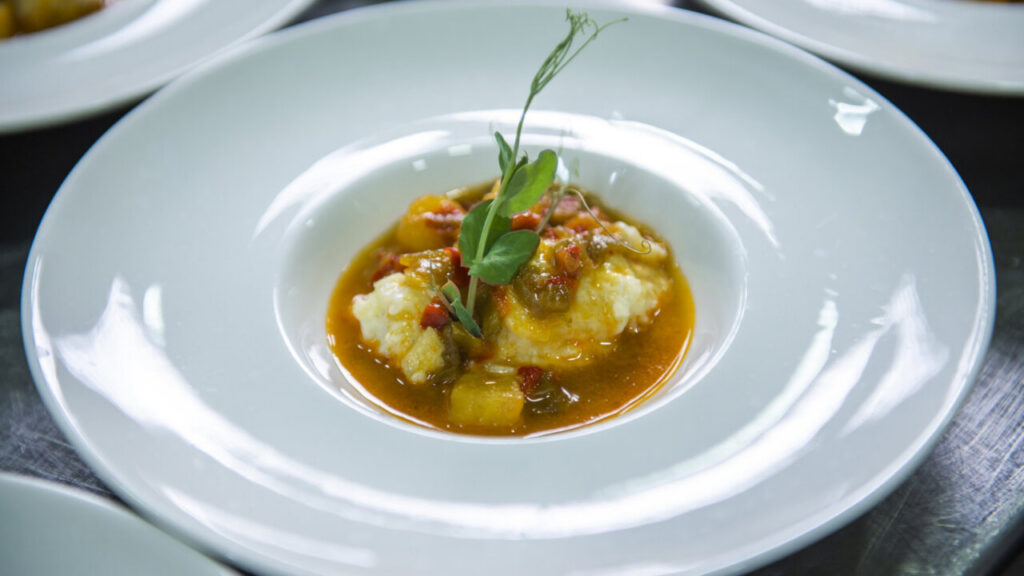 Caldillo de vendimia con cremoso de patata y bacalao en un plato blanco