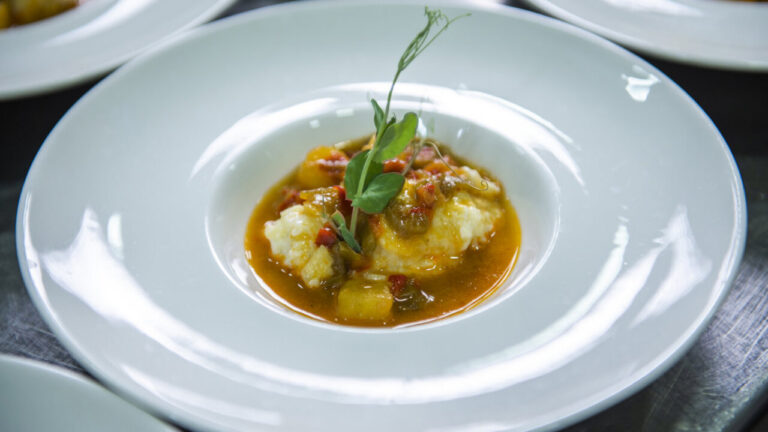 Caldillo de vendimia con cremoso de patata y bacalao en un plato blanco