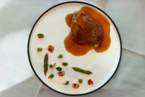 Plato gourmet con carne y decoración de verduras en Carande, Navacerrada.